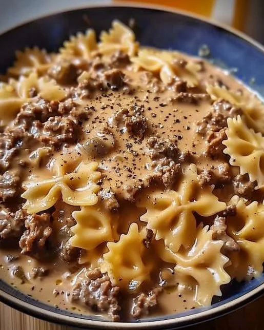 Creamy beef and bowtie pasta dish served in a bowl with fresh herbs