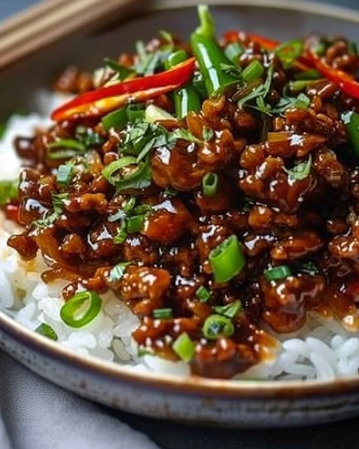 Plate of crispy chilli beef rice garnished with vegetables