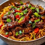 Delicious bowl of sticky beef noodles garnished with fresh herbs