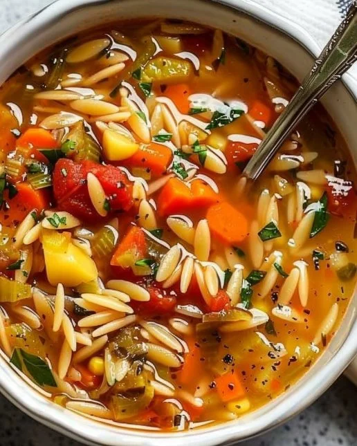A bowl of cozy vegetable orzo soup with colorful vegetables and pasta.