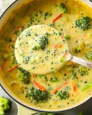 Creamy broccoli cheddar soup in a bowl, garnished with cheese and broccoli florets.
