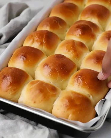 Freshly baked homemade dinner rolls on a wooden table