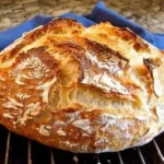 Freshly baked no-knead Dutch oven crusty bread on a wooden surface