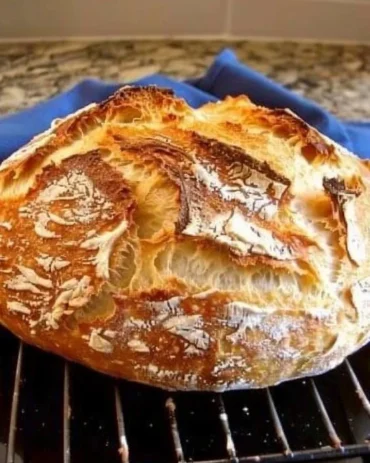 Freshly baked no-knead Dutch oven crusty bread on a wooden surface