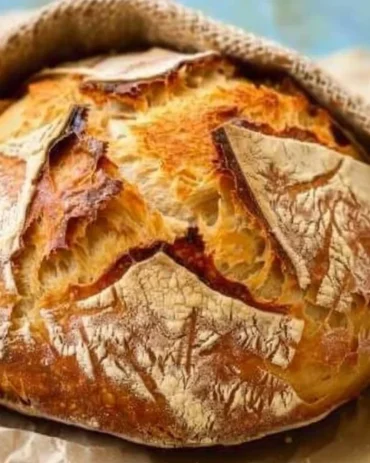 Freshly baked no-knead bread loaf on a wooden cutting board